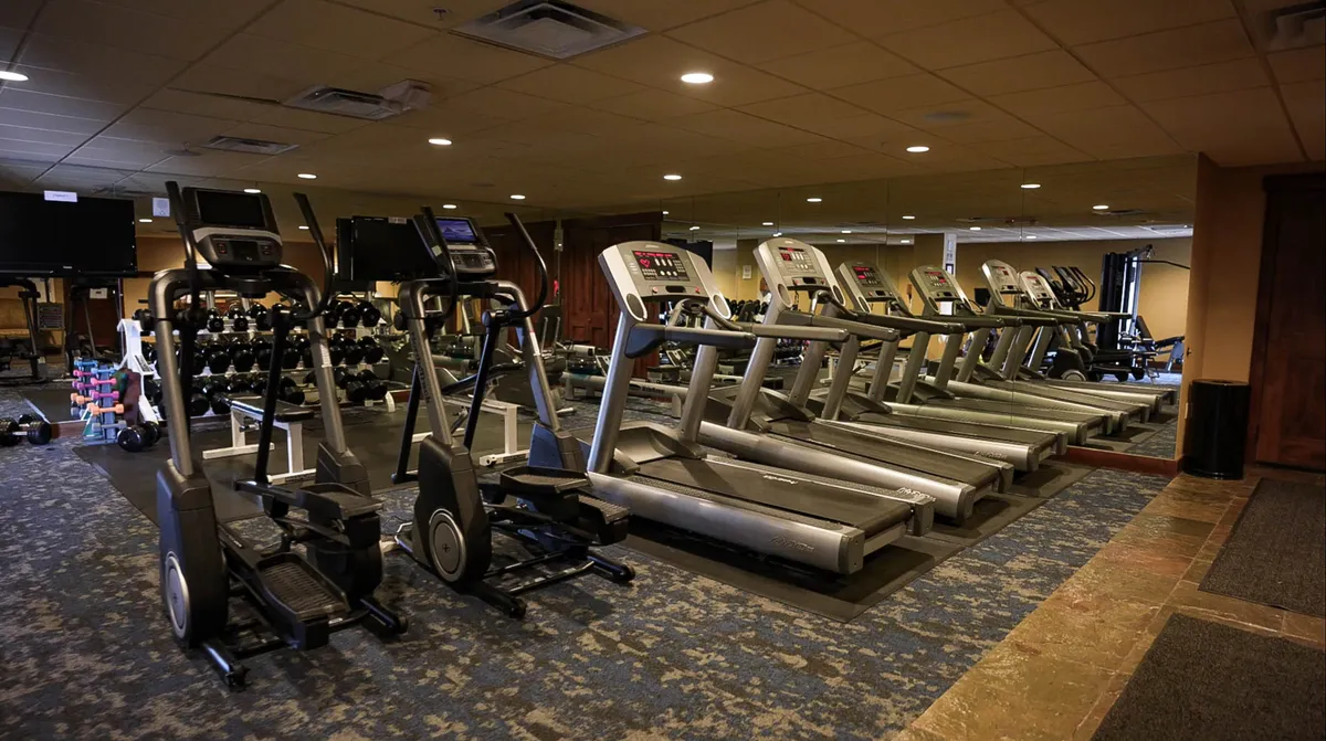 A well-equipped fitness center featuring treadmills, elliptical machines, and a selection of dumbbells. The room is bright and modern, designed to motivate guests to stay active during their stay.