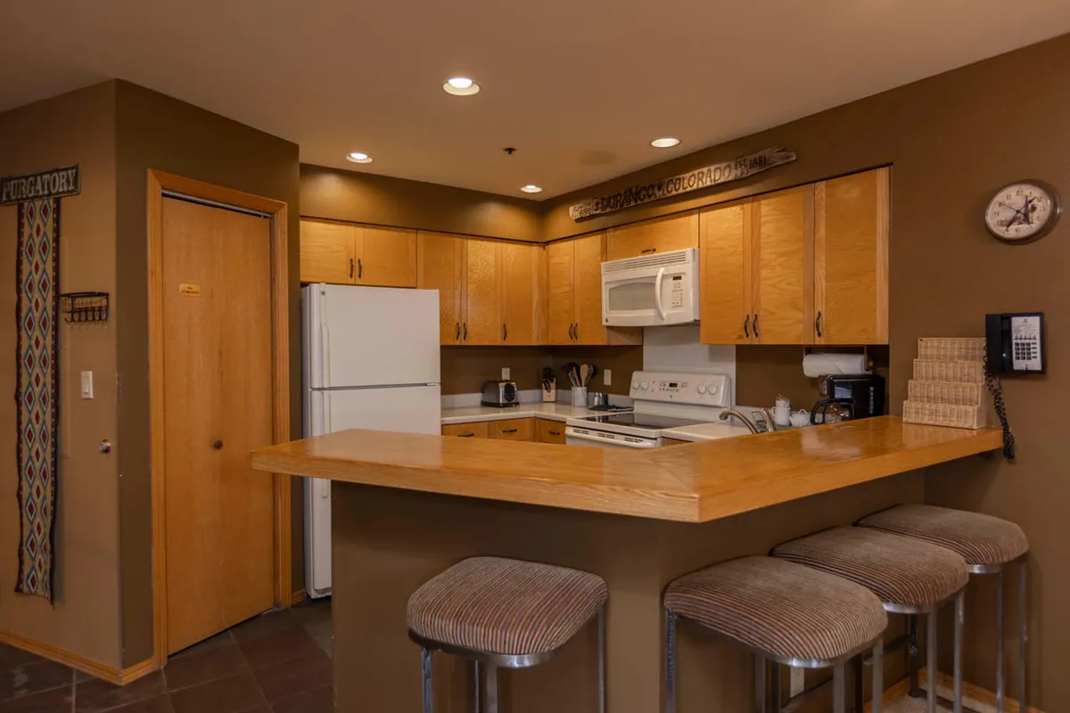 A cozy, modern kitchen with a large island, bar stools, and high-end appliances. The setup invites communal meals and post-adventure gatherings, with plenty of space for cooking and socializing after a day outdoors.
