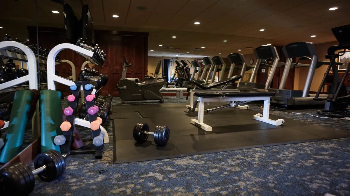 A well-equipped fitness center featuring treadmills, a weight bench, and a range of free weights. The space is designed for both cardio and strength training, offering guests a motivational atmosphere to stay active even when they're indoors.